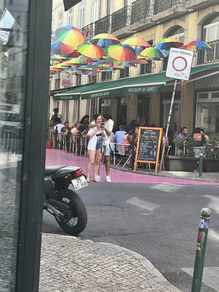 Influencers in public spaces posing for a photo on a street under colorful umbrellas