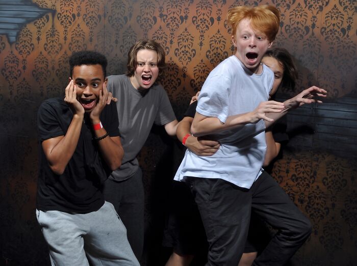 A group of startled teenagers caught in a haunted house photo.