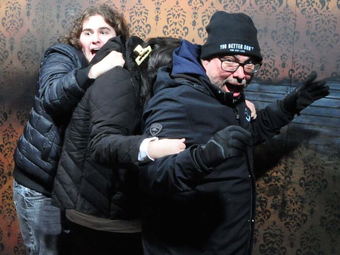 Three people huddled together in fear inside a haunted house photo.