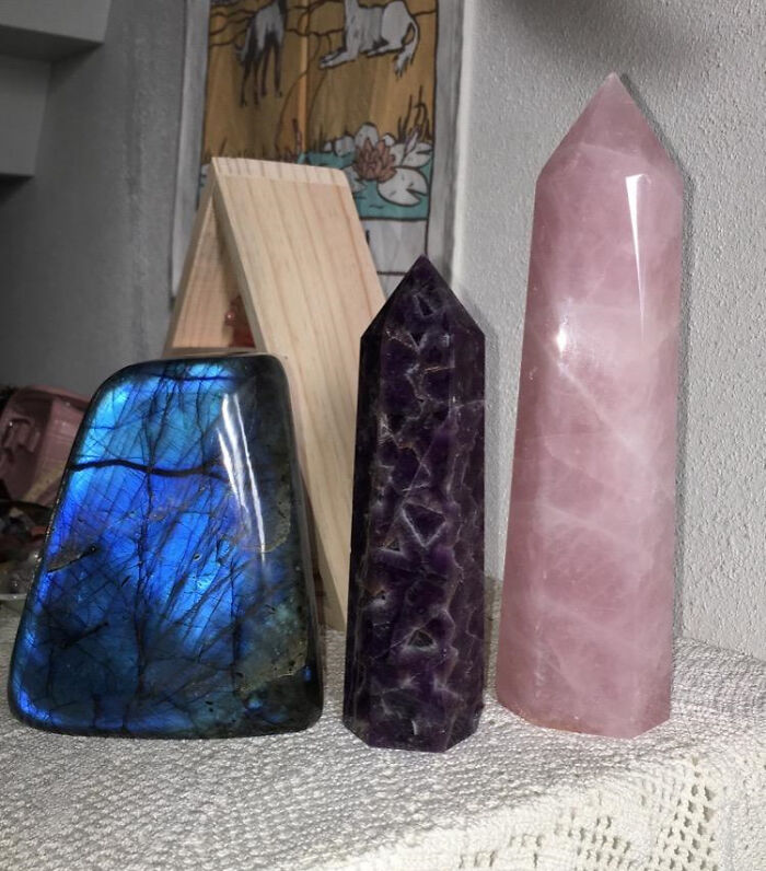 Three colorful polished gemstone towers in blue, purple, and pink on a shelf from thrift store finds