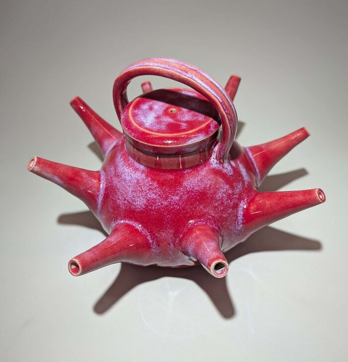 Spiky red teapot displaying unique pottery creations with a multi-spout design