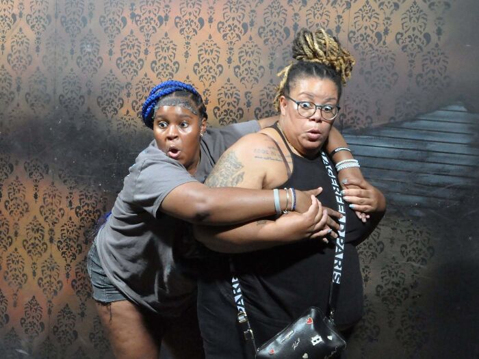Funny haunted house photo showing two terrified women clinging to each other in fear