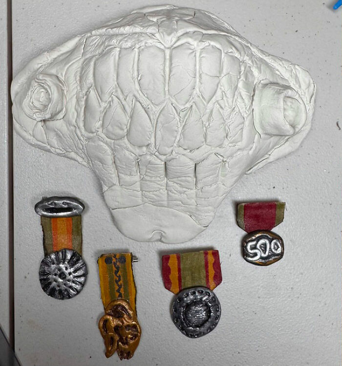 An unpainted clay Immortan Joe mask and small medals for a Mad Max Furry Road photoshoot.