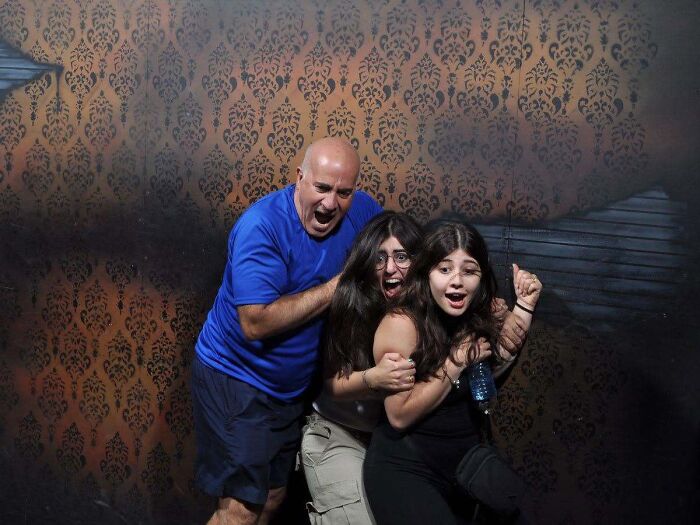A scared father and daughters reacting in fear inside a haunted house photo