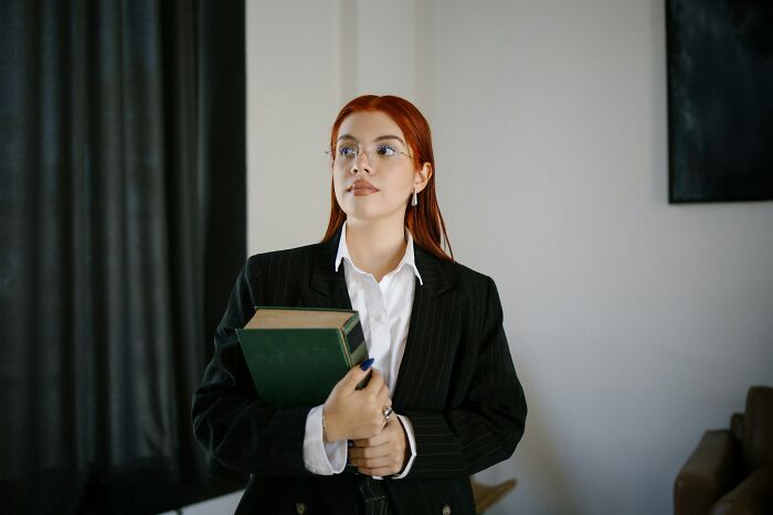 A thoughtful woman holding a green book, representing the choice when marriages collapsed