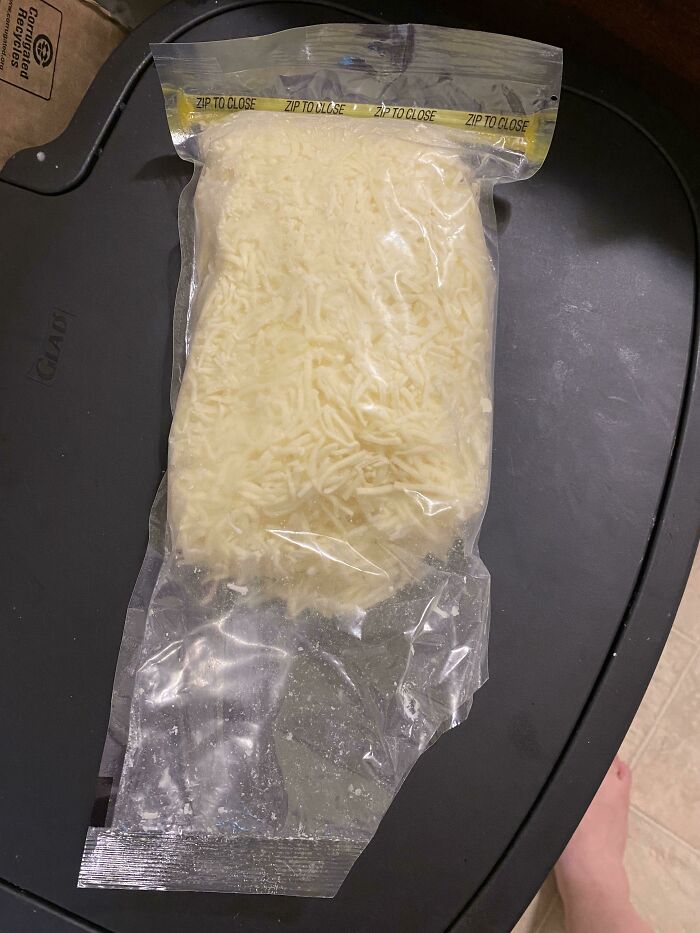 A plastic bag of shredded cheese opened from the bottom instead of the zip seal