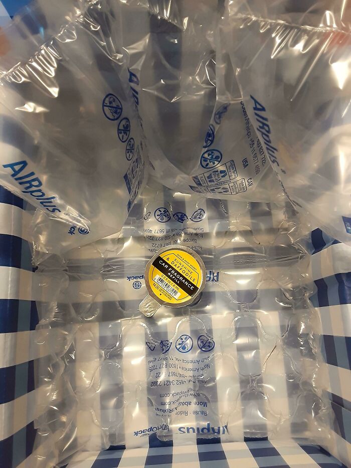 Tiny car fragrance refill surrounded by massive air pillows showing bad packaging fails.