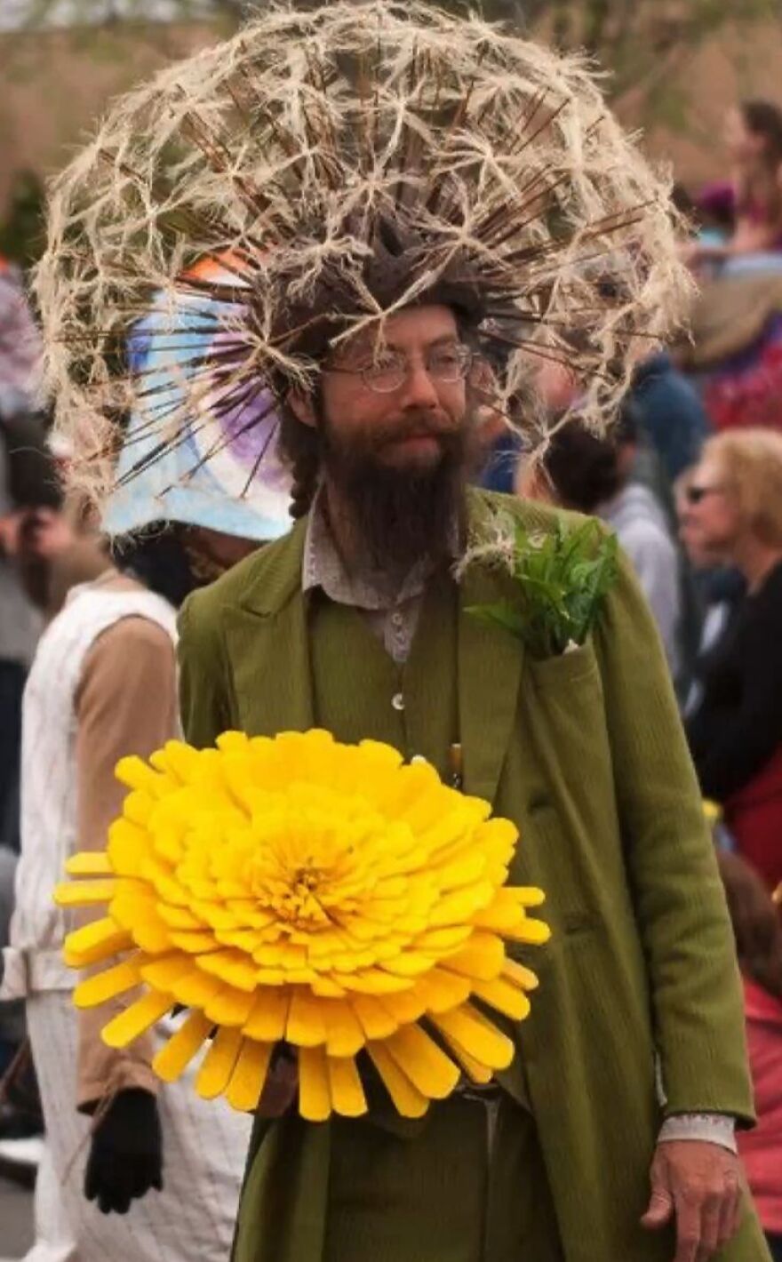 Man wearing a dandelion puff headpiece and green suit with a yellow flower, a creative Halloween costume idea