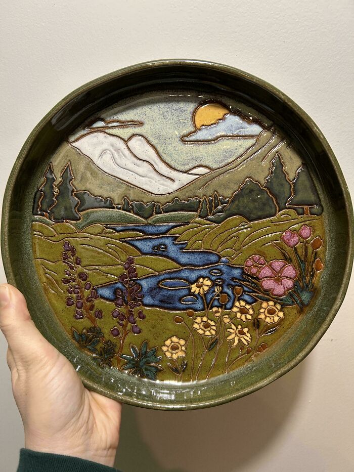 Decorative plate with a hand-painted landscape, highlighting pottery creations.