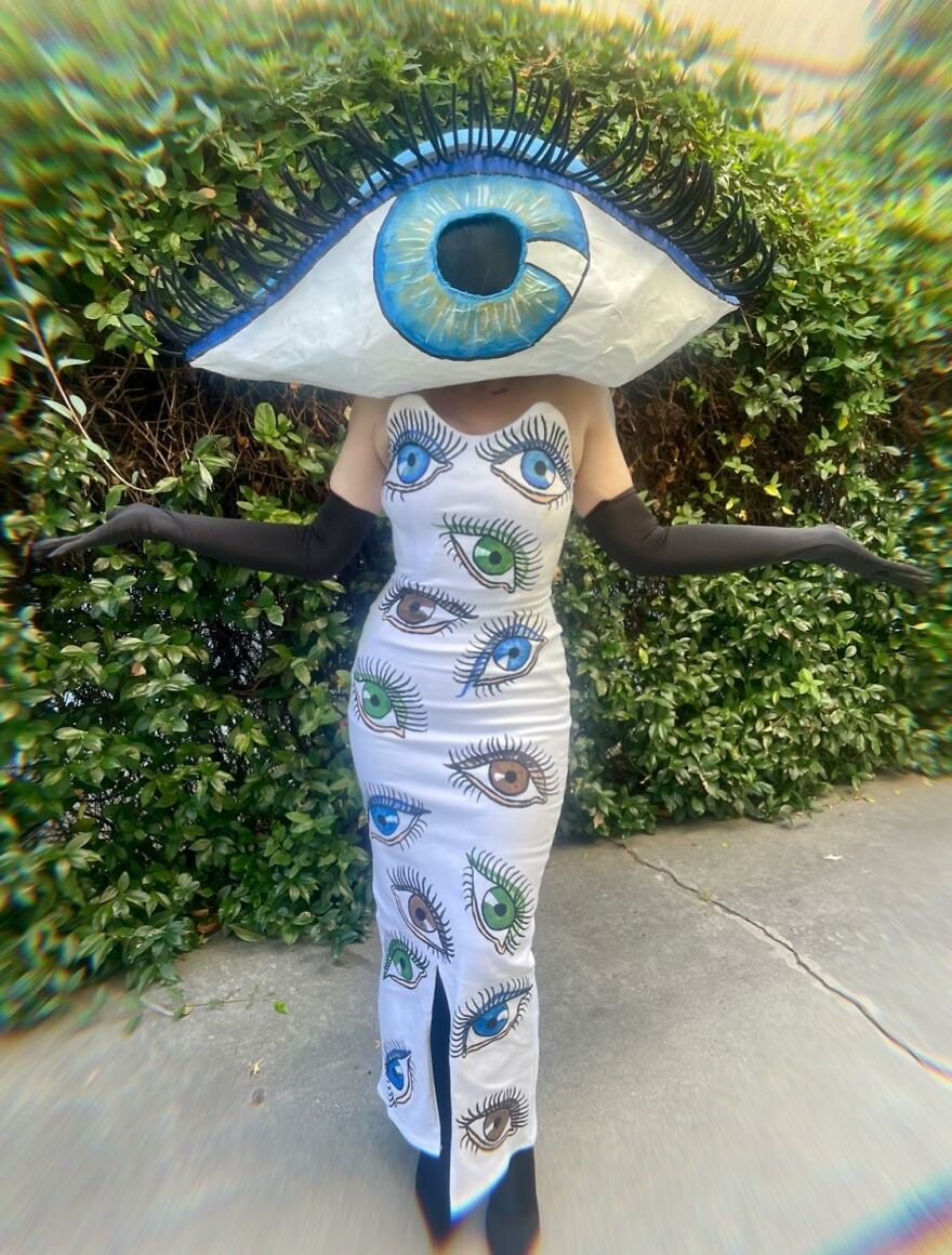A person in a white dress and giant headpiece decorated with eyes, presenting unique creative Halloween costume ideas.