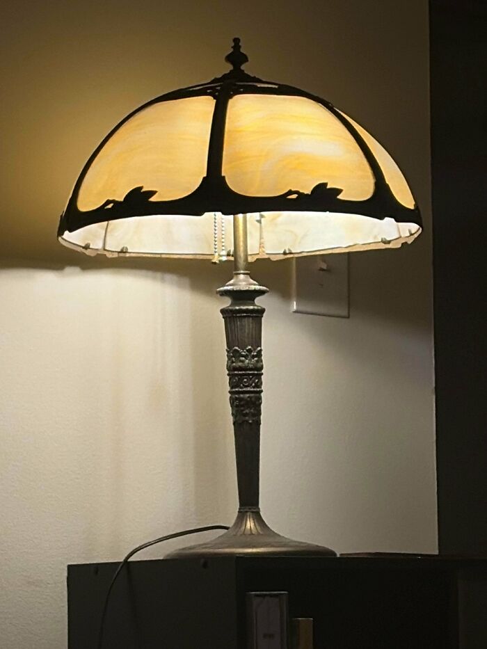 An elegant antique table lamp with a curved glass shade, a classic thrift store find.