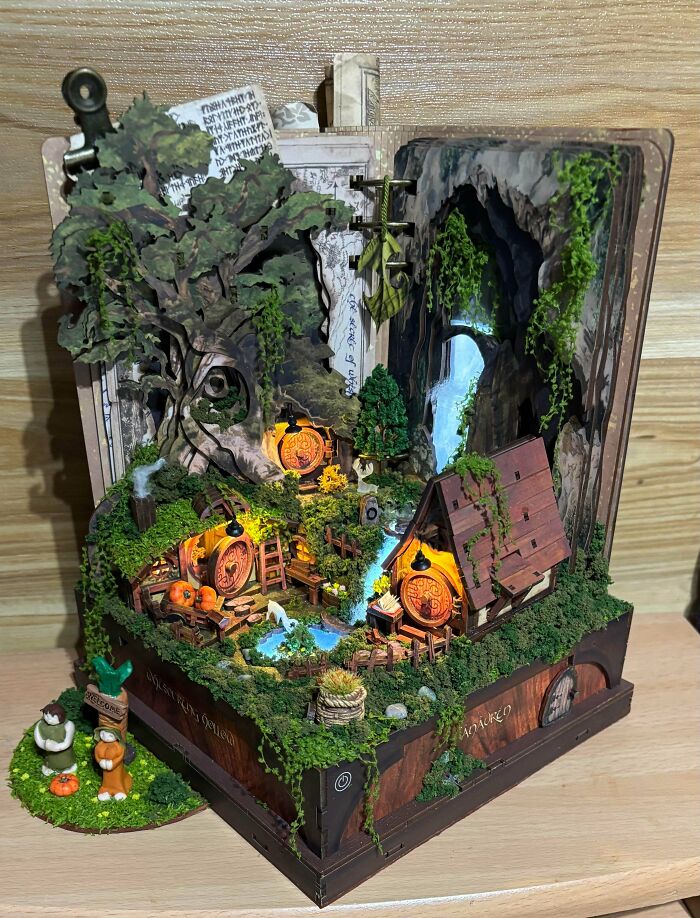 A detailed book nooks insert featuring a miniature fantasy hobbit garden with cozy lighted homes