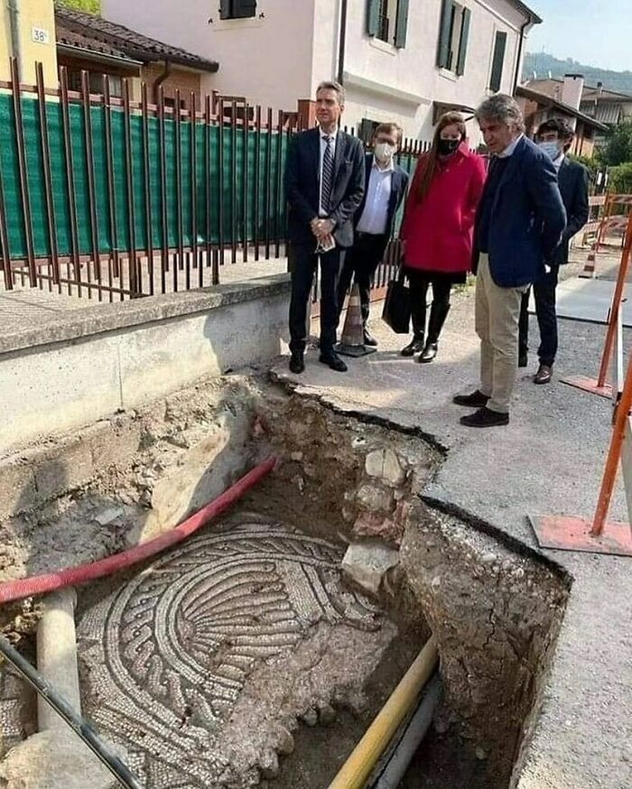 People observing an ancient Roman mosaic floor uncovered underground, highlighting facts about the past.