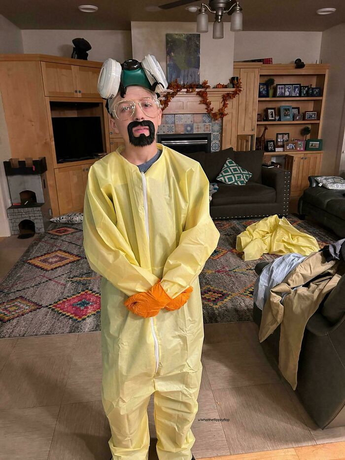Kid wearing a Walter White Breaking Bad hazmat suit Halloween costume indoors.