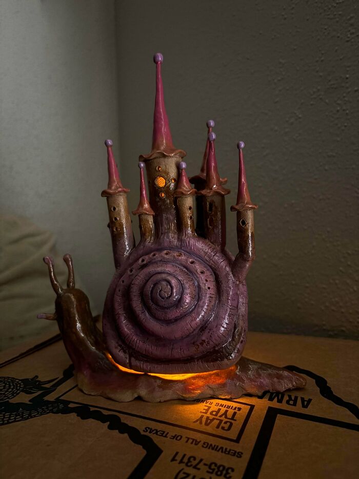 A glowing ceramic snail house lamp representing creative pottery creations