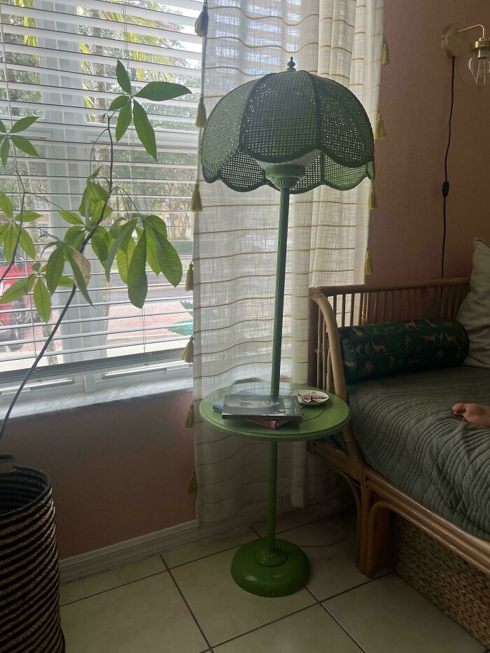 A green floor lamp with a built-in small table and woven shade, styled as cozy thrift store finds.