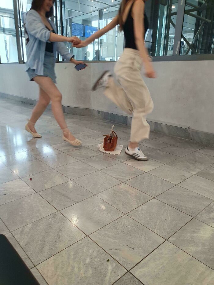 Influencers hold hands and pose while jumping in a public hallway space.
