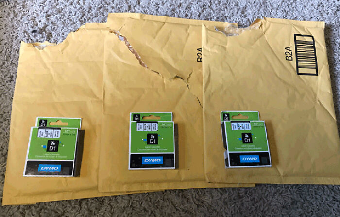 Three small label cassettes in huge padded envelopes, showing wasteful packaging fails.
